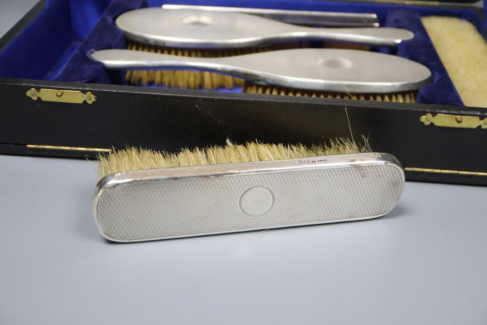 A cased George V six-piece engine-turned silver-mounted dressing table set, London, 1920/21&22.